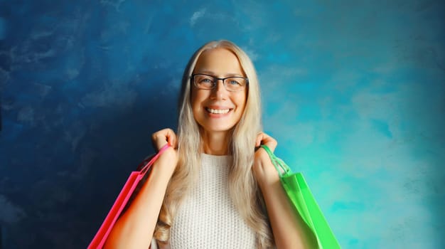 Portrait of beautiful happy smiling middle aged woman posing with colorful shopping bags in eyeglasses on studio background