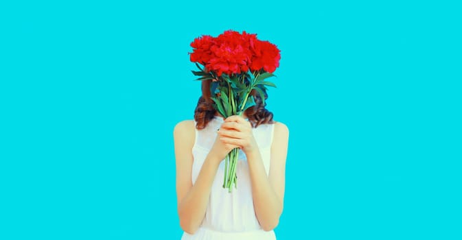 Portrait of woman covering her head with bouquet of red rose flowers on blue background