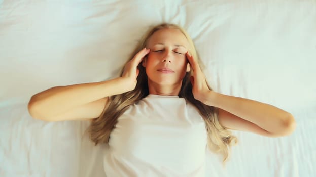 Upset exhausted woman with headache, pain tension in the head, suffers from migraine lying on the bed on pillow in bedroom at home