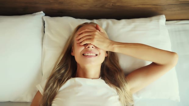 Healthy sleep, happy relaxed sleepy woman waking up while lying on bed on pillow in bedroom at home