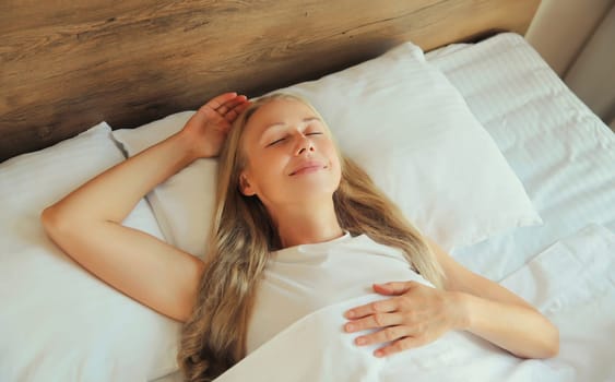 Woman sleeping lying in bed on white soft comfortable pillow in bedroom at home