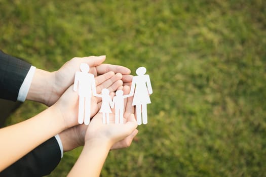 Background of paper family icon held in hand symbolize dedication to environmental friendly lifestyle of modern family, parenthood guiding sustainable lifestyle to their children. Gyre