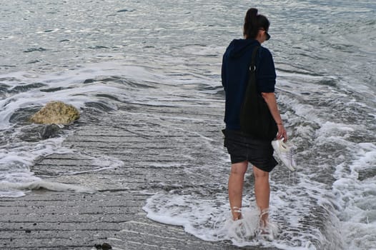 woman walks barefoot along the Mediterranean Sea in Cyprus in winter 2023