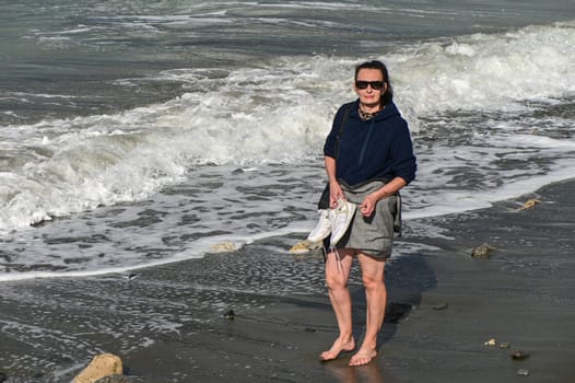 woman walks barefoot along the Mediterranean Sea in Cyprus in winter 2023 2