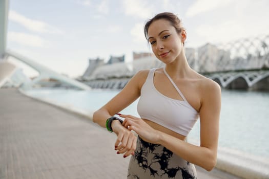Young fit woman looking at smartwatch and counting calories burned. Healthy life concept