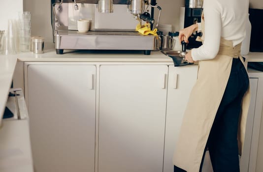 Close-up of barista using a tamper to press ground coffee into a portafilter at the coffee shop