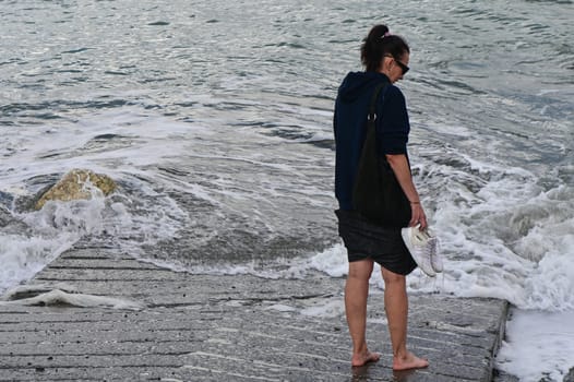 woman walks on the waves of the Mediterranean Sea in Cyprus in winter 2023