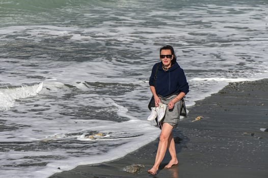 woman walks barefoot along the Mediterranean Sea in Cyprus in winter 2023 9