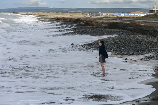 woman walking barefoot on the beach of the Mediterranean Sea in Cyprus in winter 2