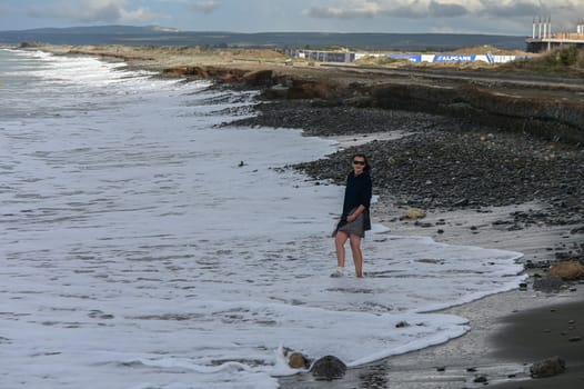 woman walking barefoot on the beach of the Mediterranean Sea in Cyprus in winter 1