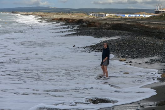 woman walking barefoot on the beach of the Mediterranean Sea in Cyprus in winter