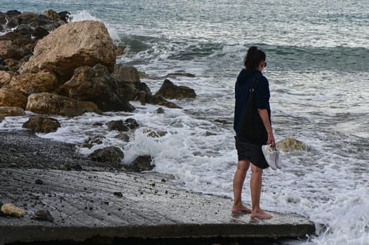 woman walks along the Mediterranean coast in Cyprus in winter 2023