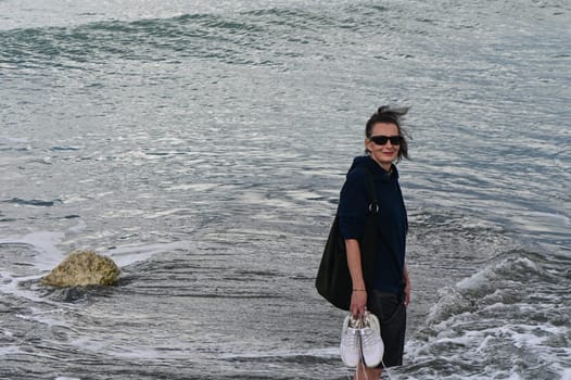 woman walks on the waves of the Mediterranean Sea in Cyprus in winter 2023 1