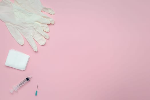 Flat lay of syringes, gauze, and latex gloves on a pink background for the concept of medical and healthcare