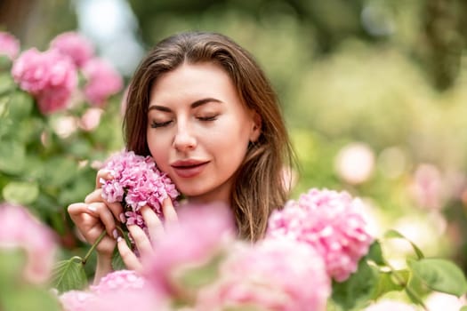 Hydrangeas Happy woman in pink dress amid hydrangeas. Large pink hydrangea caps surround woman. Sunny outdoor setting. Showcasing happy woman amid hydrangea bloom