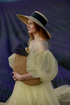 Woman poses in lavender field. Happy woman in yellow dress holds lavender bouquet. Aromatherapy concept, lavender oil, photo session in lavender.