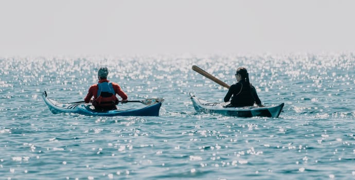 Happy smiling woman in kayak on ocean, paddling with wooden oar. Calm sea water and horizon in background