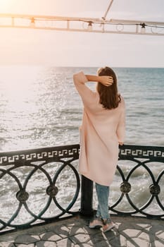 Woman travel sea. Young Happy woman in a long red dress posing on a beach near the sea on background of volcanic rocks, like in Iceland, sharing travel adventure journey