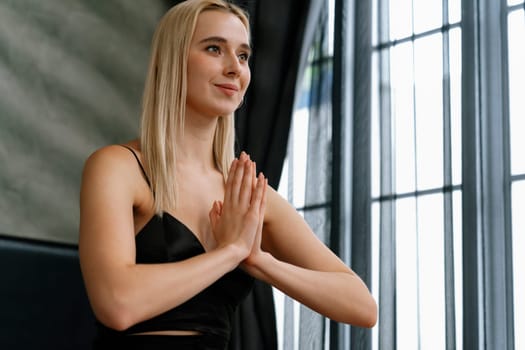 Young woman doing morning yoga and meditation in her bedroom, enjoying the solitude and practicing meditative poses. Mindfulness activity and healthy mind lifestyle. Blithe