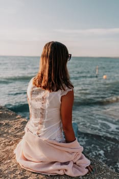 Woman travel sea. Young Happy woman in a long red dress posing on a beach near the sea on background of volcanic rocks, like in Iceland, sharing travel adventure journey