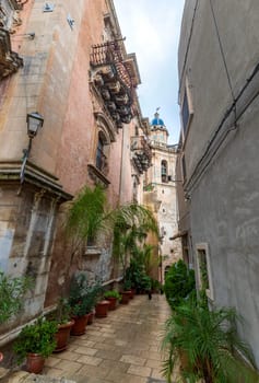 Small stone street with flowers in the Ragusa Ibla city in Sicily, Italy