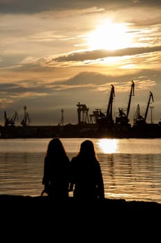 two friends looking at amazing sunset at the harbor