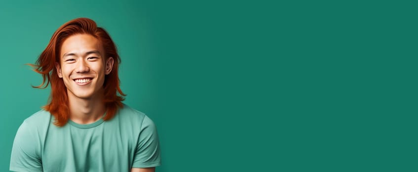 Handsome young man guy smile Asian with long red hair, on a light green background, banner, copy space, portrait. Advertising of cosmetic products, spa treatments, shampoos and hair care products, dentistry and medicine, perfumes and cosmetology men