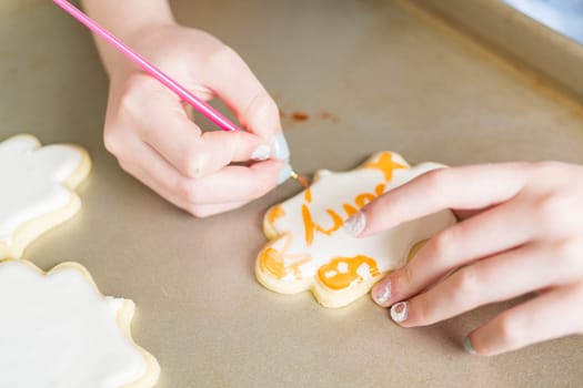 A heartwarming scene of a little girl carefully writing 'Sorry' on sugar cookies with food coloring, the cookies beautifully flooded with white royal icing.