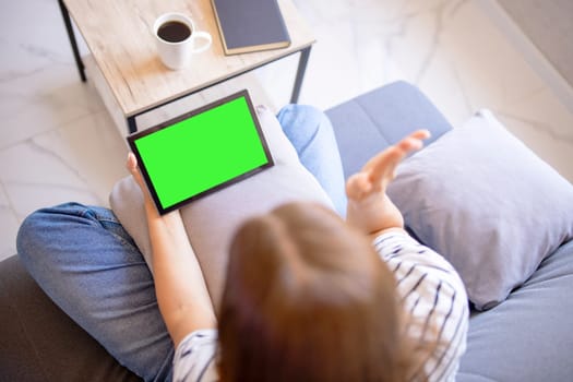 Over-shoulder view of a tablet with a green screen held by a person