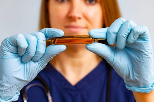 Focused healthcare worker holding a glass ampoule with medication carefully.