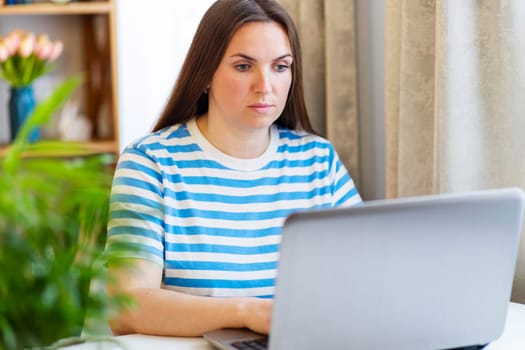 Focused Woman Working on Laptop in a Home Setting.