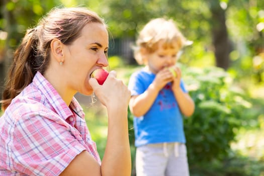 Mother and child eating apples outdoors