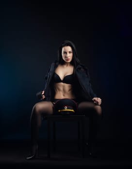 the sexy girl in a military police uniform on a dark background with handcuffs and a rubber baton