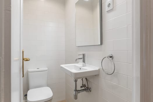 Compact and clean bathroom space with white subway tiles, modern sink, and silver fixtures.