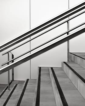 Monochromatic image capturing the linear symmetry of a modern staircase and handrails