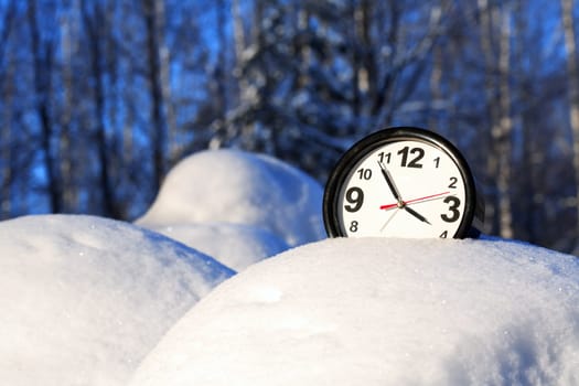 Clocks in the snow on the background of a winter landscape