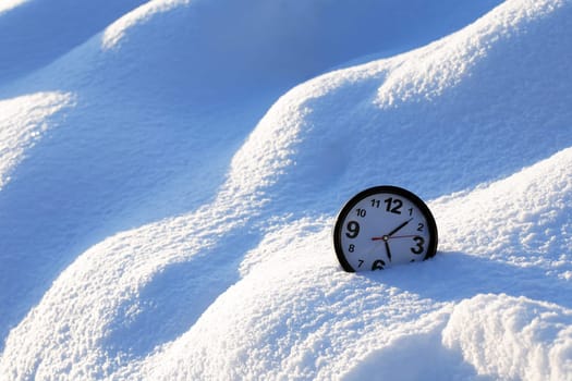 Clocks in the snow on the background of a winter landscape