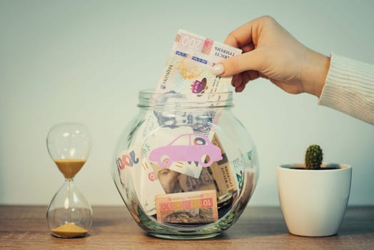 Person puts 200 hryvnias to savings bank, toned image