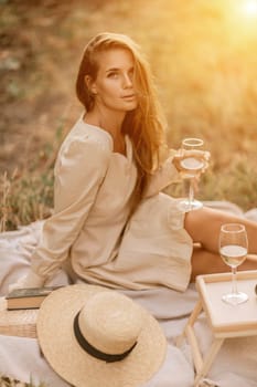 Woman picnic vineyard. Romantic dinner, fruit and wine. Happy woman with a glass of wine at a picnic in the vineyard on sunny day, wine tasting at sunset