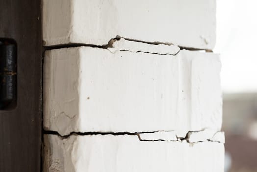 House with many cracks between bricks near door, building foundation problems