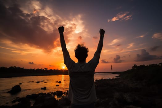 Silhouette of a happy man with his hands raised up against the backdrop of a sunset or dawn.