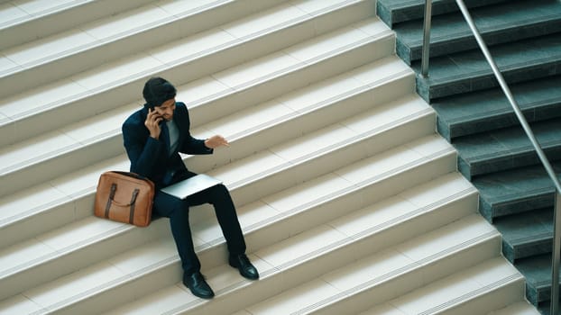 Top view business man celebrate successful project while sitting at stairs. Smart project manager getting new job, getting promotion, increasing sales while calling friends by using phone. Exultant.