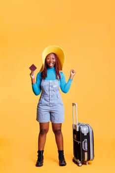 Smiling person being excited about trip, using passport to travel on international holiday destination. Female adult leaving on urban adventure with trolley bags, weekend activities.