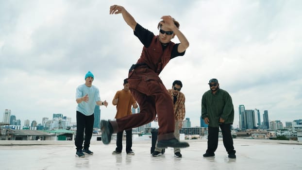 Professional asian street dancer practice B boy dance while multicultural friends at roof top. Young modern dancing group doing hip hop movement. Style,fashion,action. Outdoor sport 2024. Endeavor.