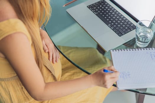 Beautiful pregnant woman working on laptop. Young businesswoman working in her office.