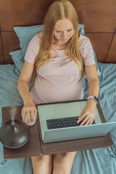 Multitasking expectant woman enhances her home workspace, using an aroma diffuser for a soothing atmosphere while working during pregnancy.