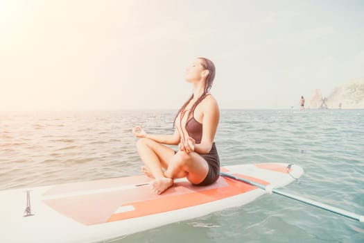 Woman sup yoga. Happy young sporty woman practising yoga pilates on paddle sup surfboard. Female stretching doing workout on sea water. Modern individual female outdoor summer sport activity