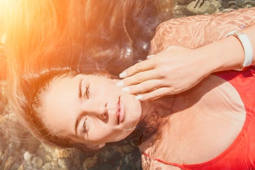 Side view a Young beautiful sensual woman in a mint long dress posing on a volcanic rock high above the sea during sunset. Girl on the nature on overcast sky background. Fashion photo