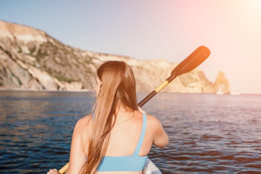 Woman in kayak back view. Happy young woman with long hair floating in transparent kayak on the crystal clear sea. Summer holiday vacation and cheerful female people relaxing having fun on the boat