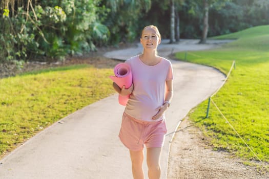 Energetic pregnant woman takes her workout outdoors, using an exercise mat for a refreshing and health-conscious outdoor exercise session.